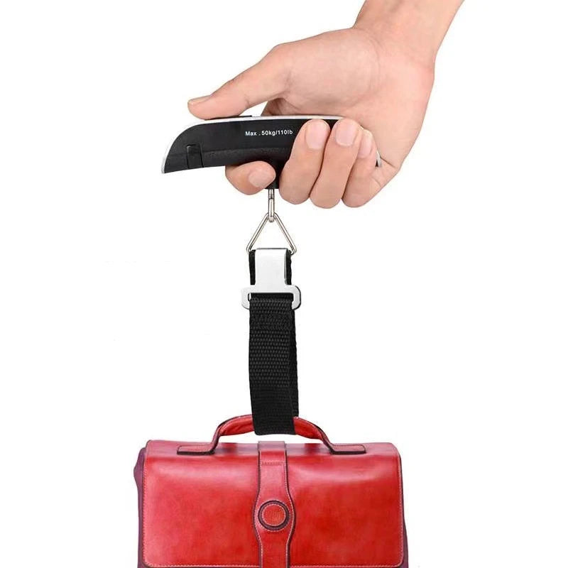 Hand holding a black strap luggage scale with metal hanging hook