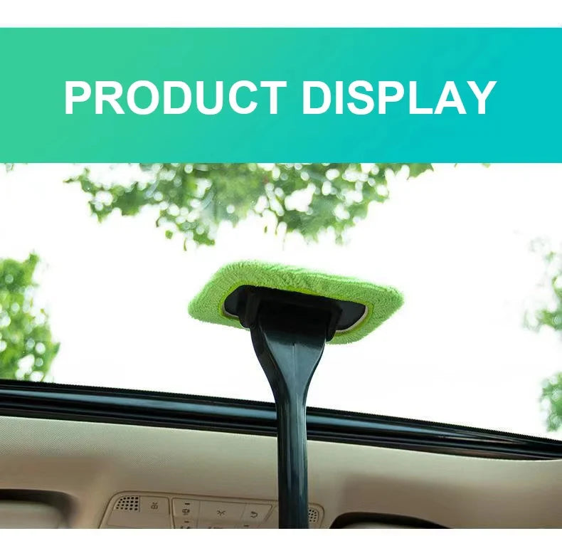 Car window cleaning brush with green microfiber pad standing on windshield glass.