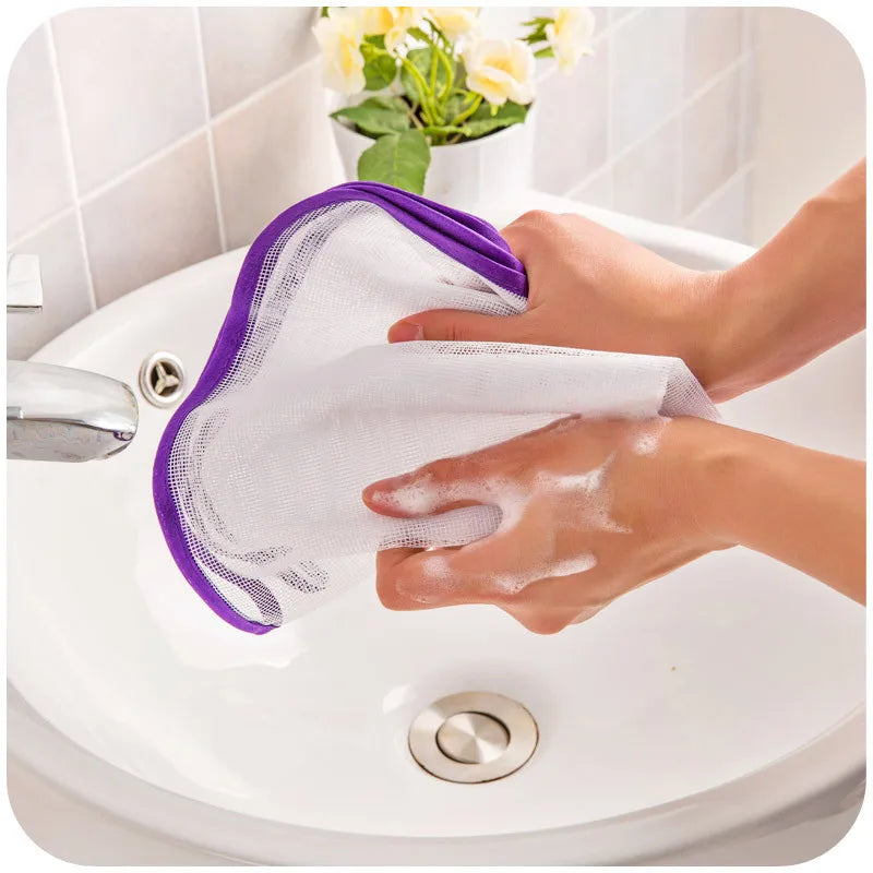 Protective mesh pressing mat cover, gray with purple trim, held under tap in sink