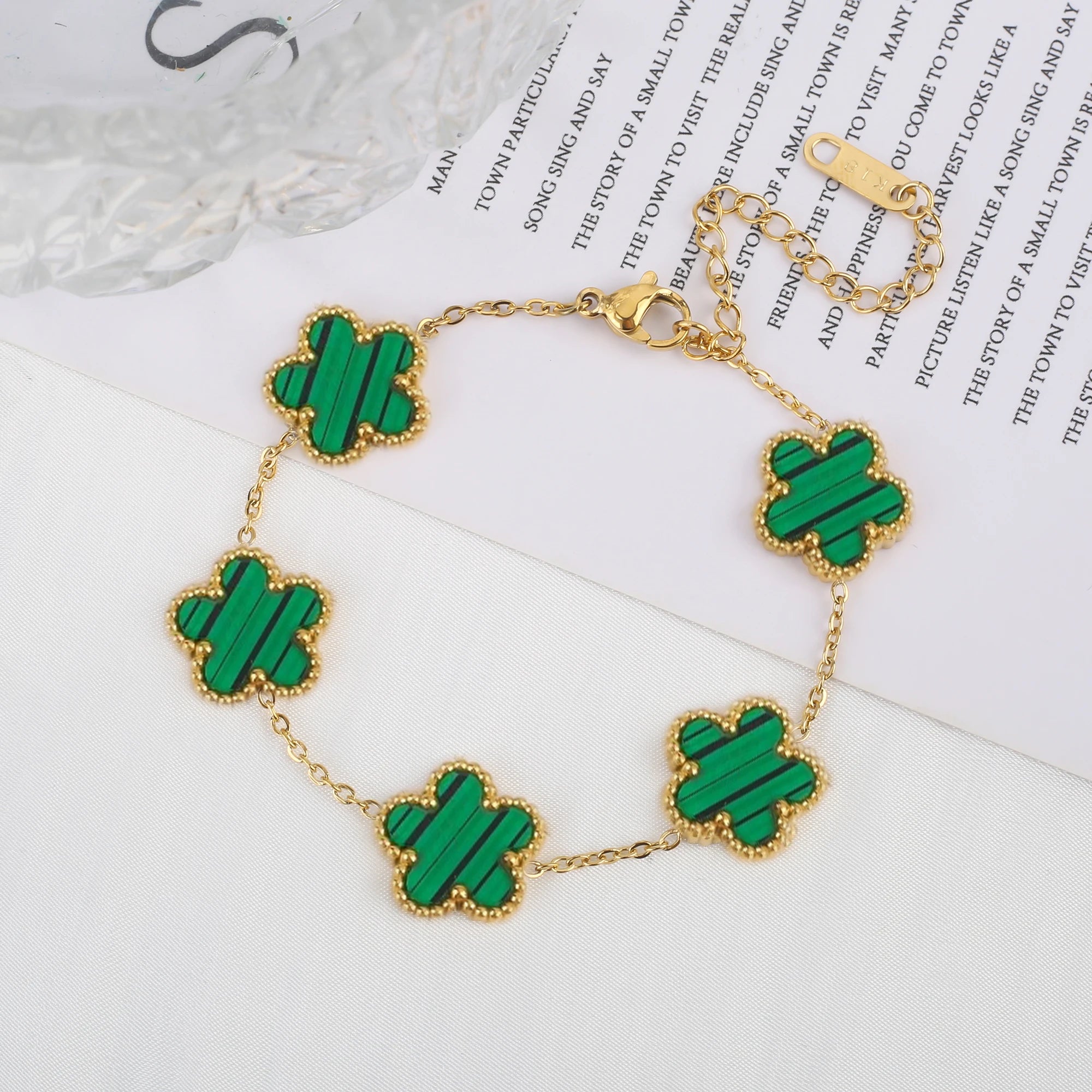 Adjustable gold bracelet with five green clover flower charms and linked chain