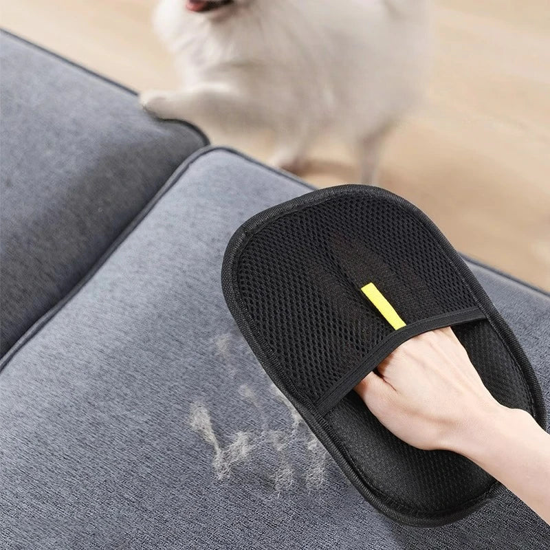 Black pet hair remover glove with yellow mark, worn on hand over fabric