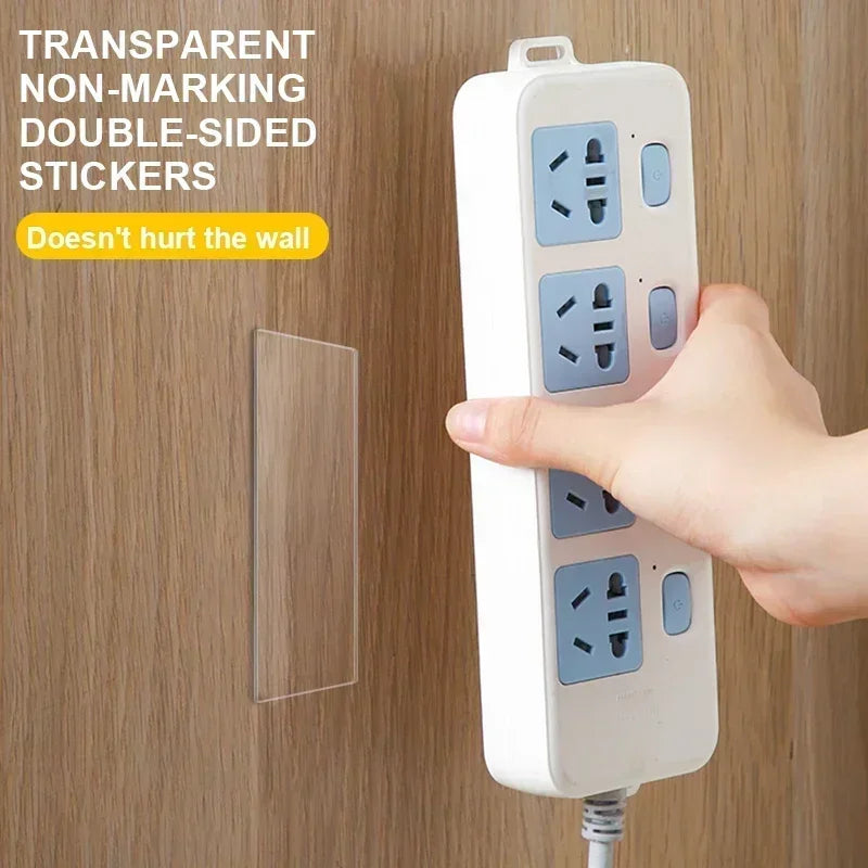 Transparent non-marking double-sided sticker strips on wall-mounted outlet, held in hand.