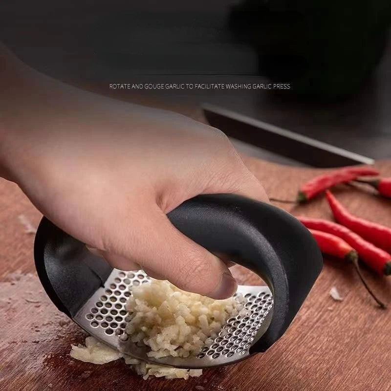 Manual garlic press crushing garlic with perforated stainless steel grater