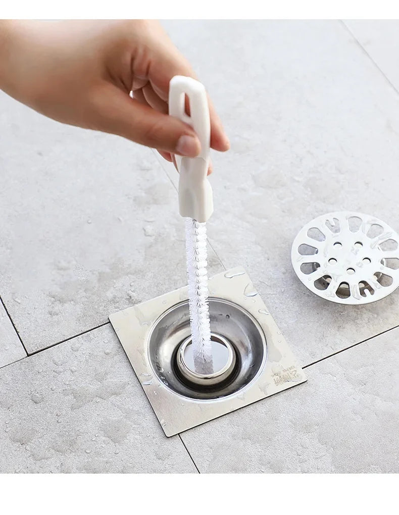 White-handled flexible drain brush with spiral bristles in sink drain opening