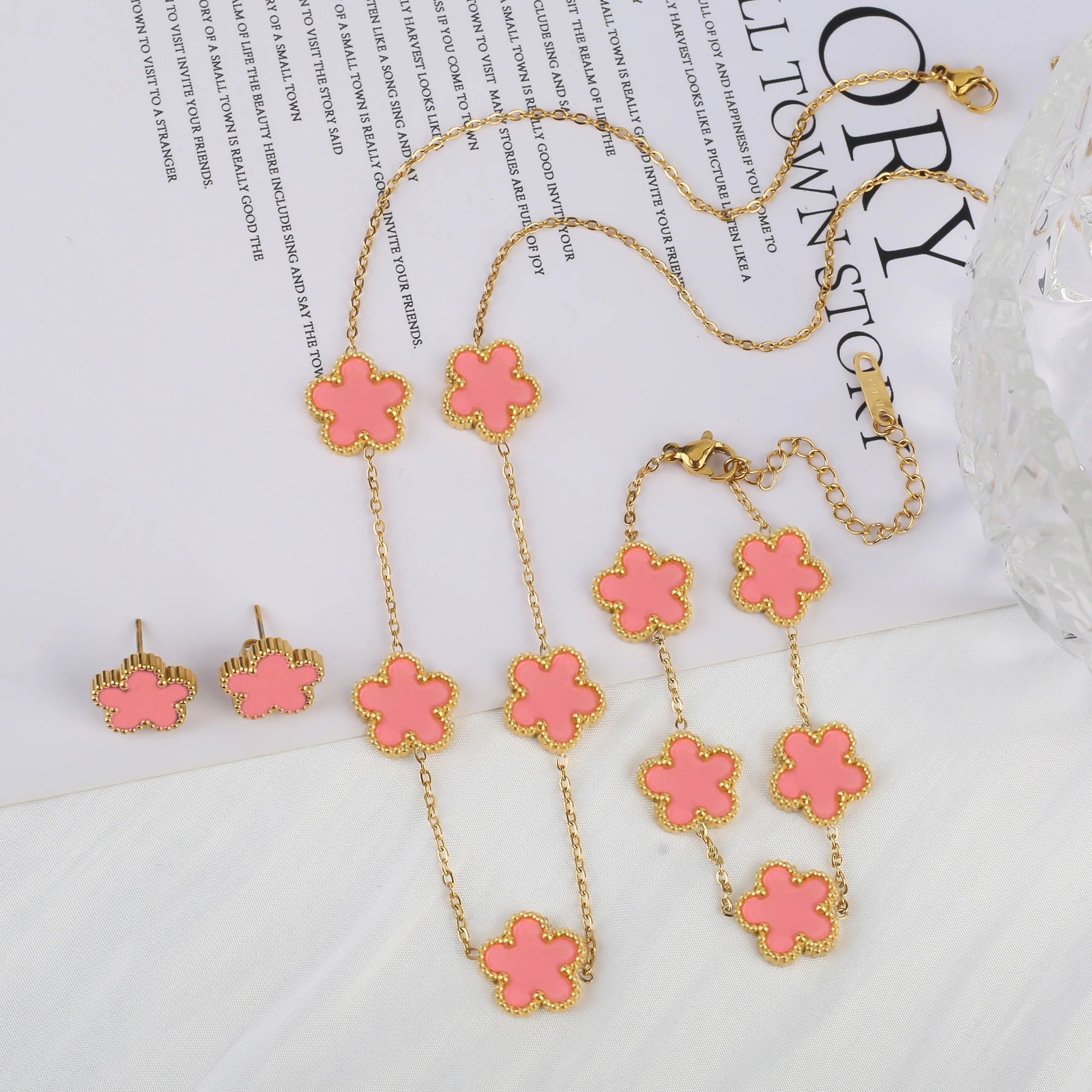 Three-piece clover jewelry set with pink enamel five-leaf charms, gold tone necklace and earrings