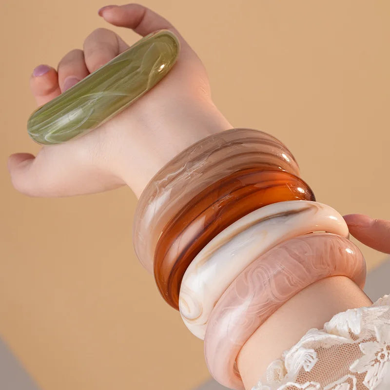 Stacked acrylic open bangles in olive green, amber, and translucent pink