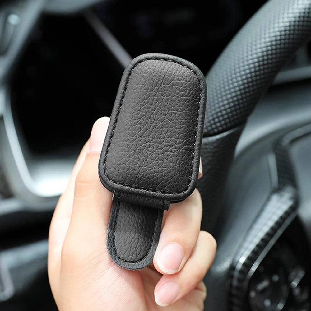 Black car sunglasses clip holder case with textured finish, held in a hand