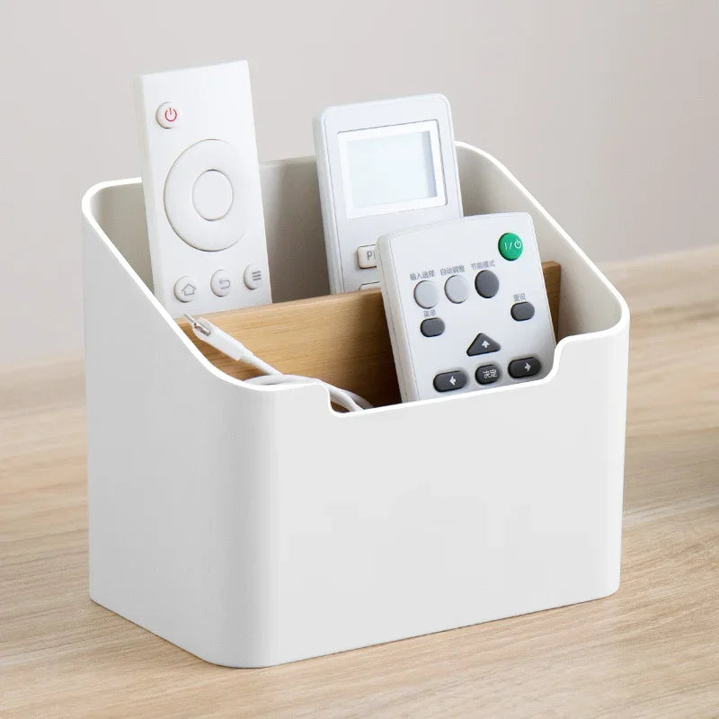 White plastic desktop storage box with open top holding remotes and tissue pack