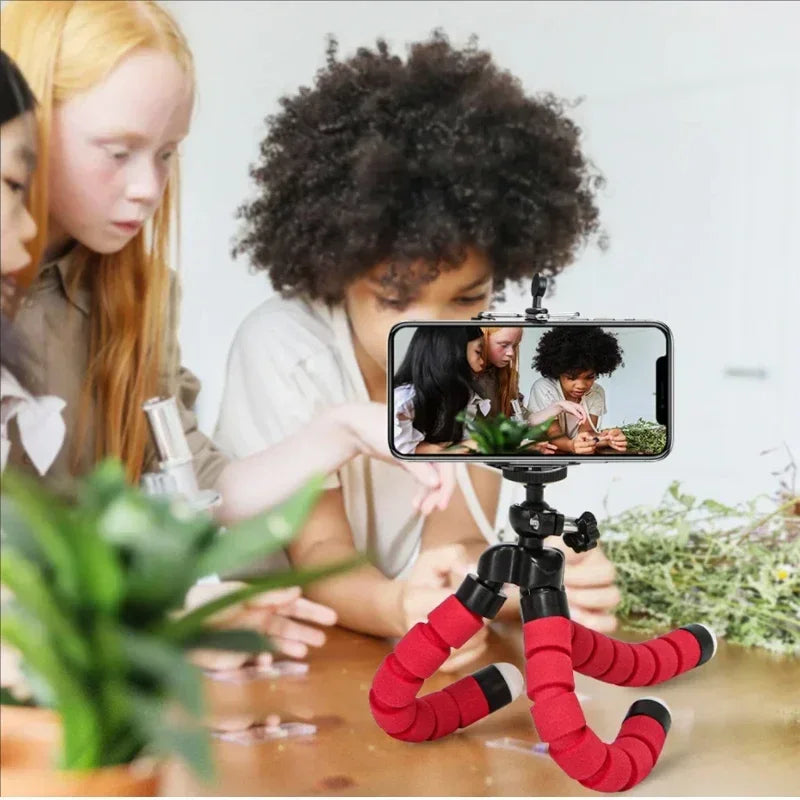 Red mini phone tripod stand with clamp and flexible legs holding a smartphone