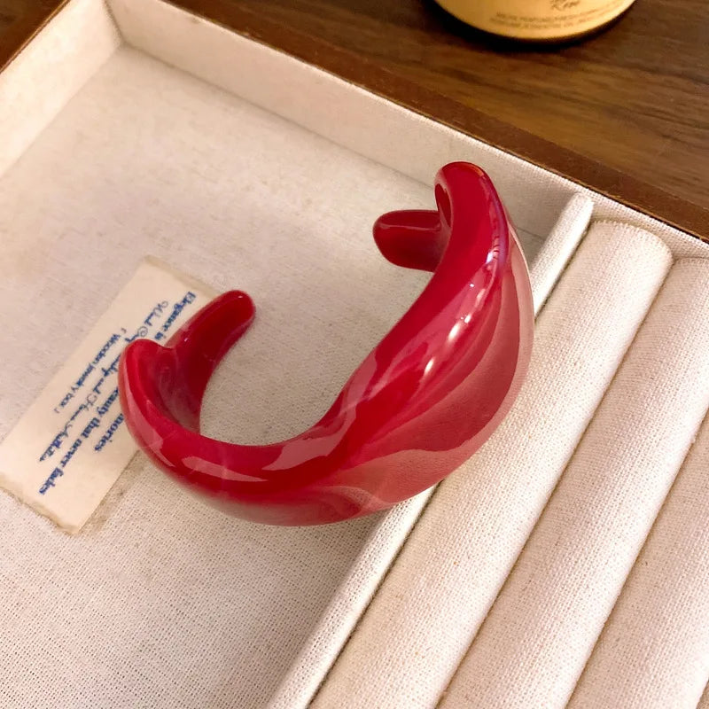 Red glossy open acrylic bangle with smooth curved shape and open cuff design