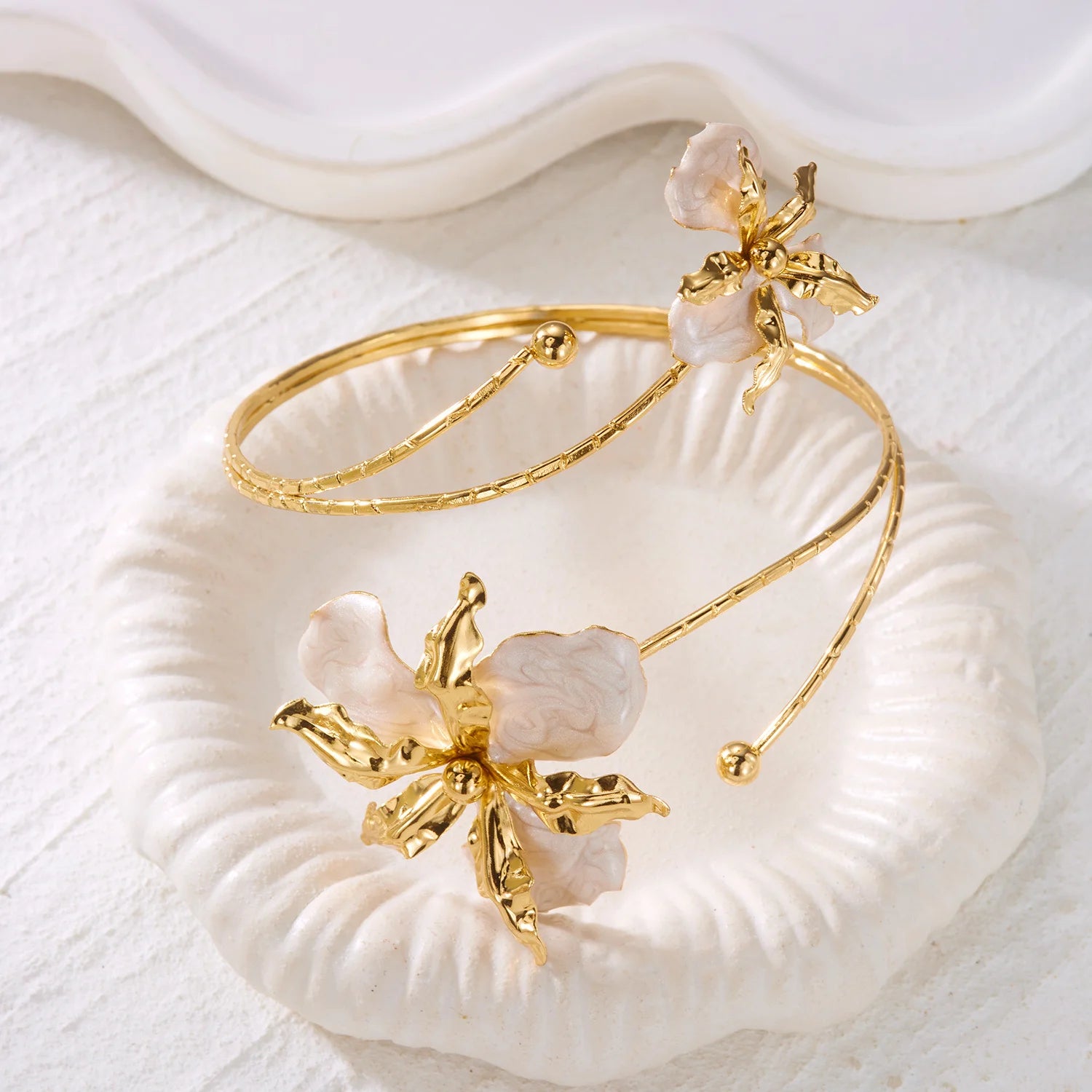 Gold open cuff arm bracelet with white enamel flower charm and bead detail accents