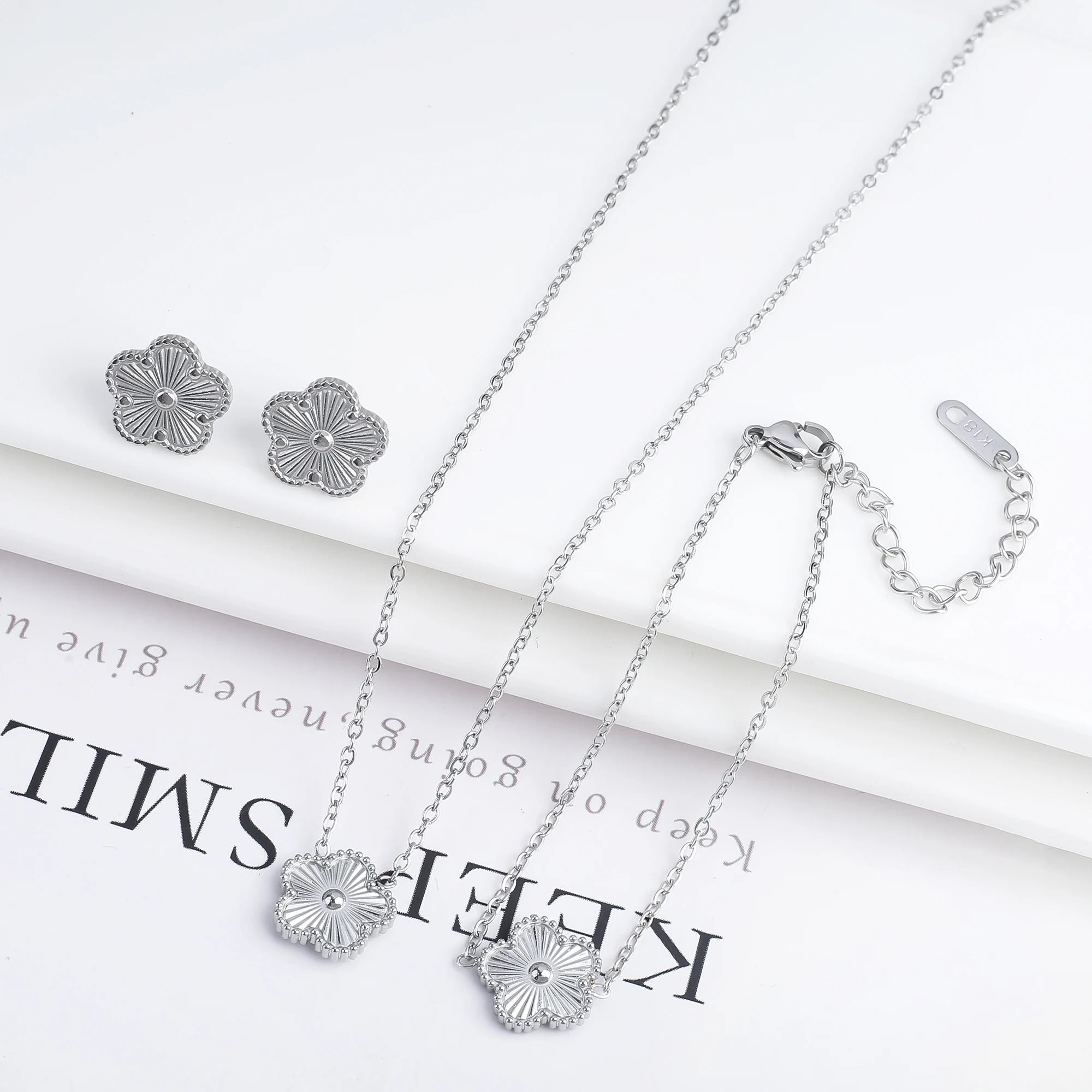 Silver-tone jewelry set with textured flower stud earrings, necklace, and bracelet
