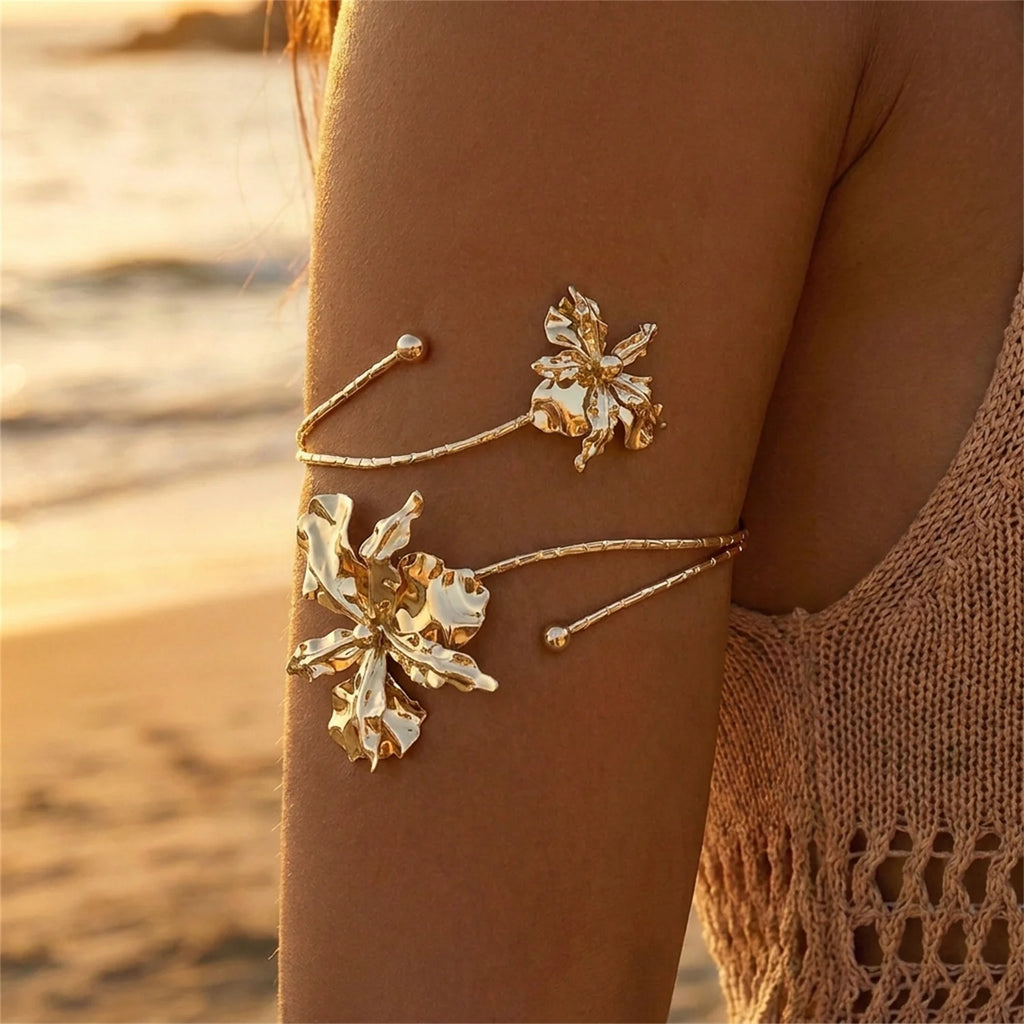 Gold-tone open cuff arm bracelet with white and gold enamel flower details and beads.