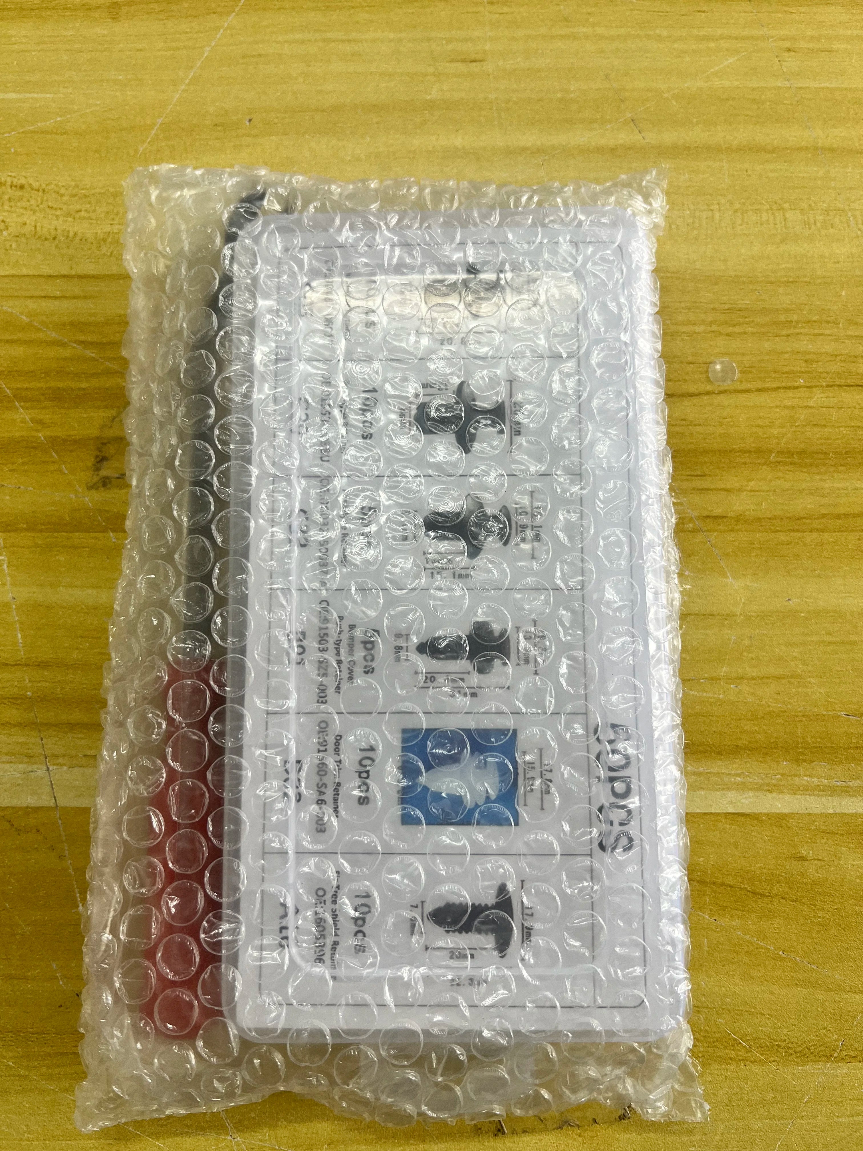 Bubble-wrapped auto fastener clip kit on a wooden surface