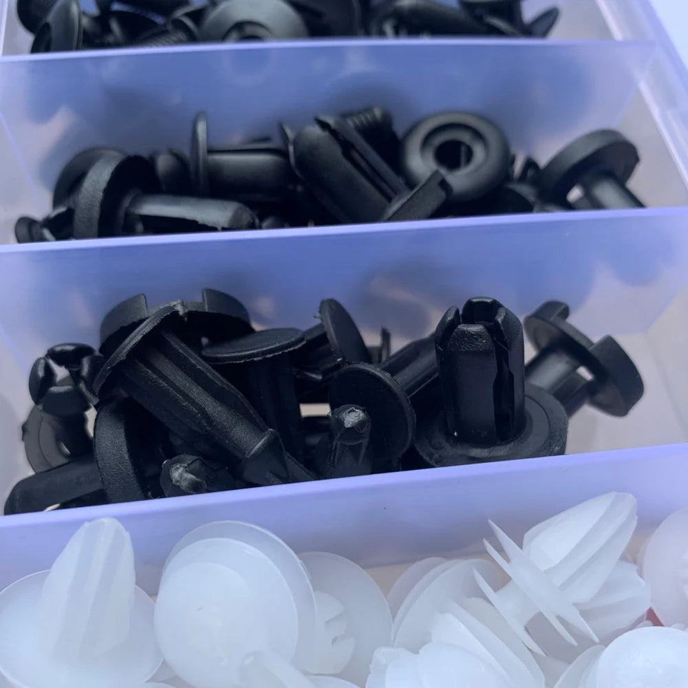 Assorted black automotive push retainer clips in a plastic organizer bin
