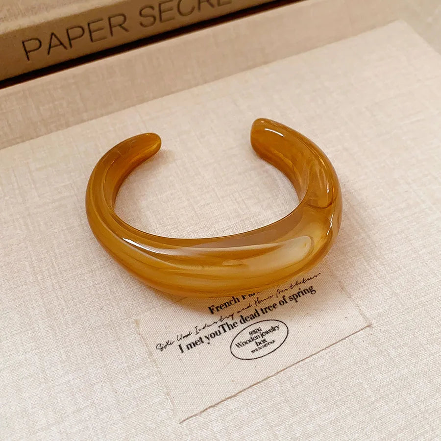 Warm amber translucent acrylic open bangle with shiny rounded face smudge design