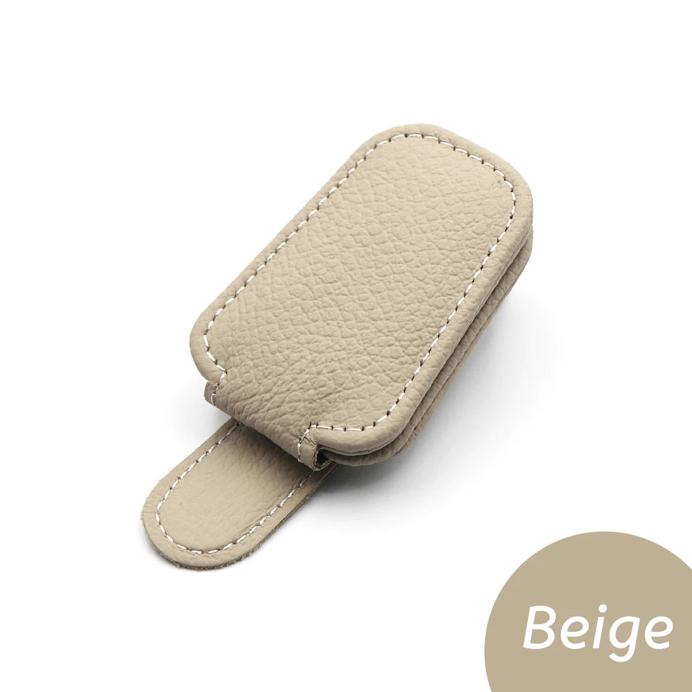 Beige car glasses clip holder with stitched leather-look finish and curved strap.