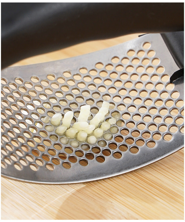 Stainless steel garlic press with perforated crusher plate and minced garlic