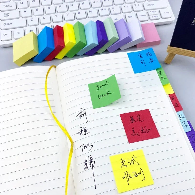 Lined memo with neon sticky flags and yellow square notes alongside a keyboard.