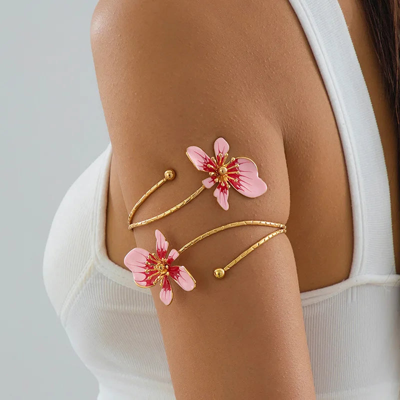 Gold-tone open cuff arm bracelet with pink enamel flower charms and bead accents.