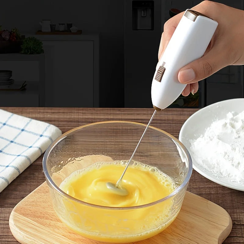 White battery milk frother held over a mixing bowl with thick foam