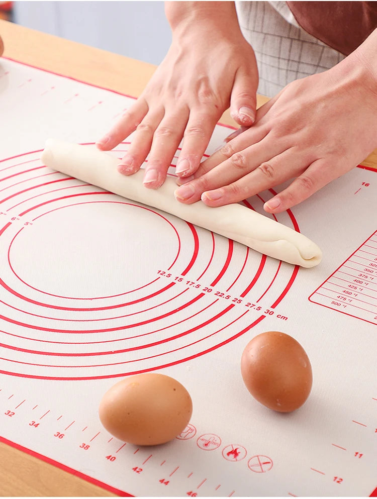 Silicone baking mat with red concentric circles, hands flattening rolled dough