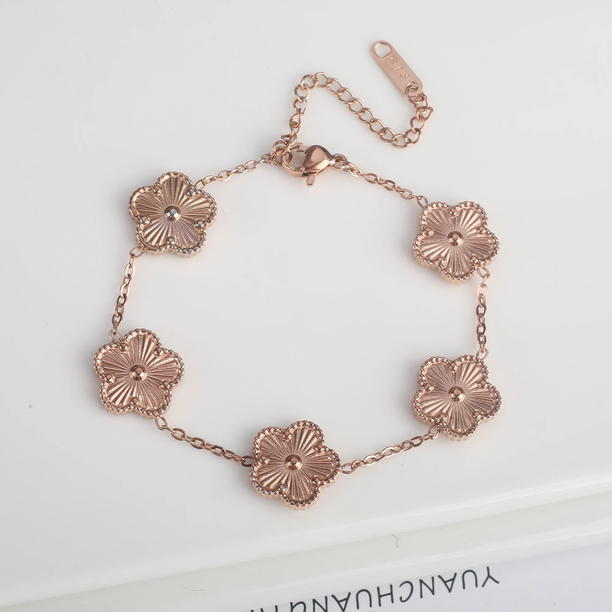Rose gold tone adjustable chain bracelet with five flower clover charms