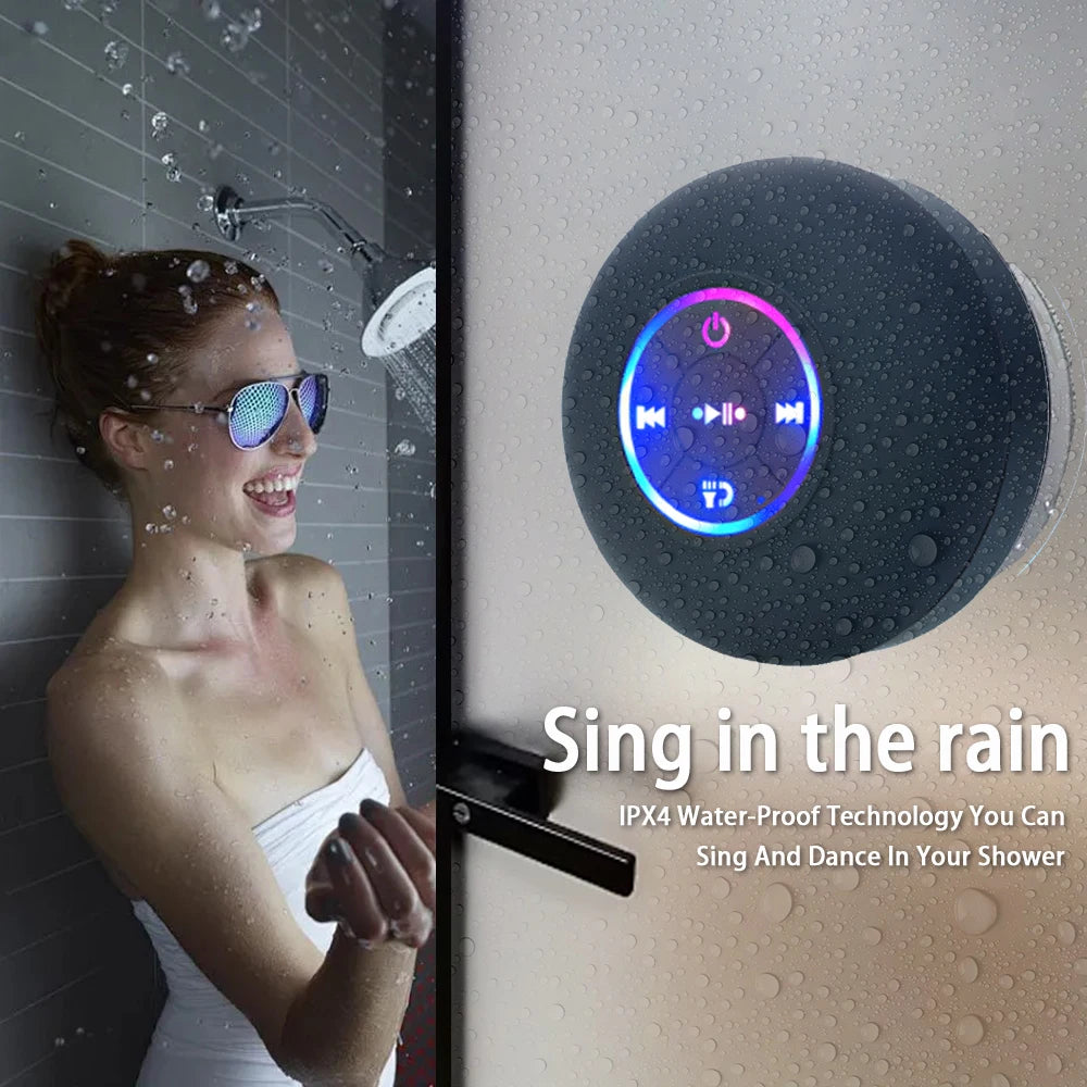 Black waterproof Bluetooth speaker with glowing RGB ring, attached on a wet wall with water droplets