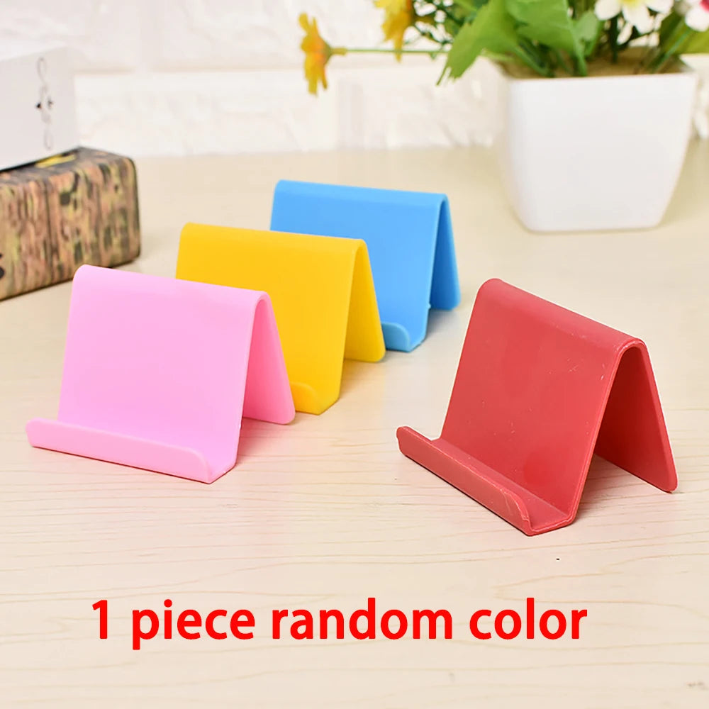 Assorted pastel plastic phone holder stands, including red and pink foldable V-shape