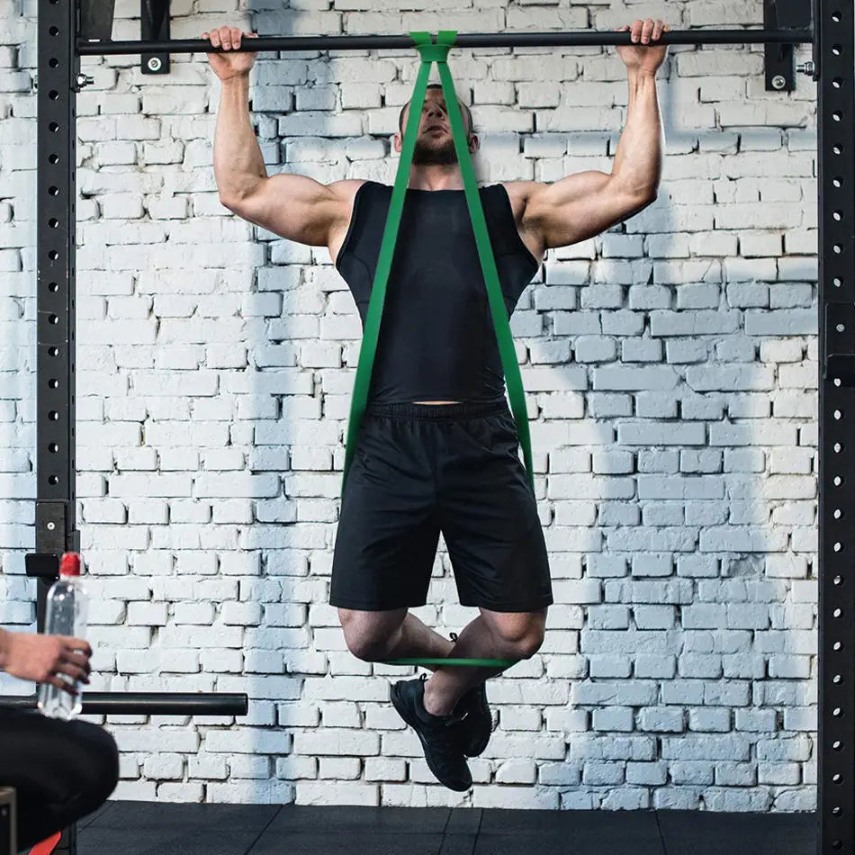 Green resistance loop band for pull-up training attached to a gym pull-up bar