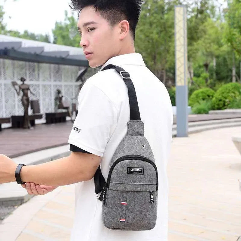Gray sling fanny pack worn crossbody with adjustable strap and front zip pocket