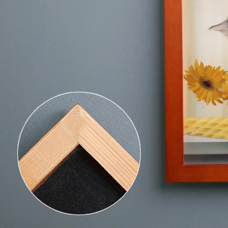 Corner view of clear adhesive strip holding a frame edge on a wall