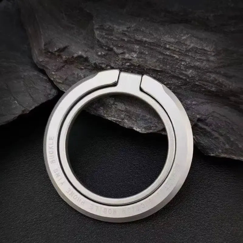 Gray/silver magnetic phone ring holder, round alloy finger loop on dark surface