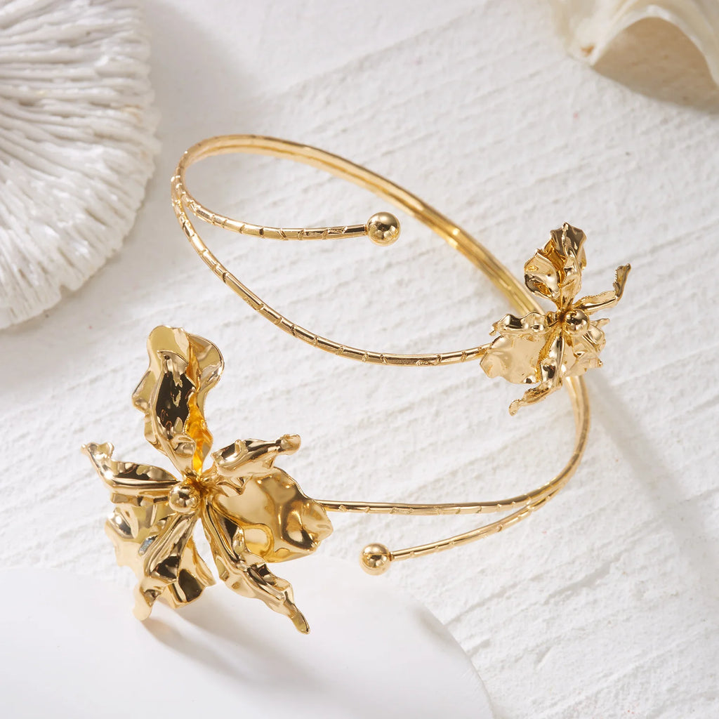 Gold-tone floral open cuff arm bracelet with two dangling white-gold flower charms.