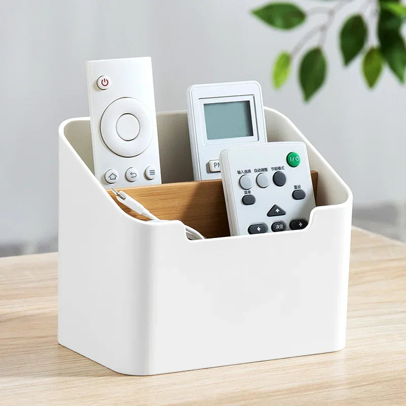 White plastic storage box with open top holding remote controls and a tissue pack