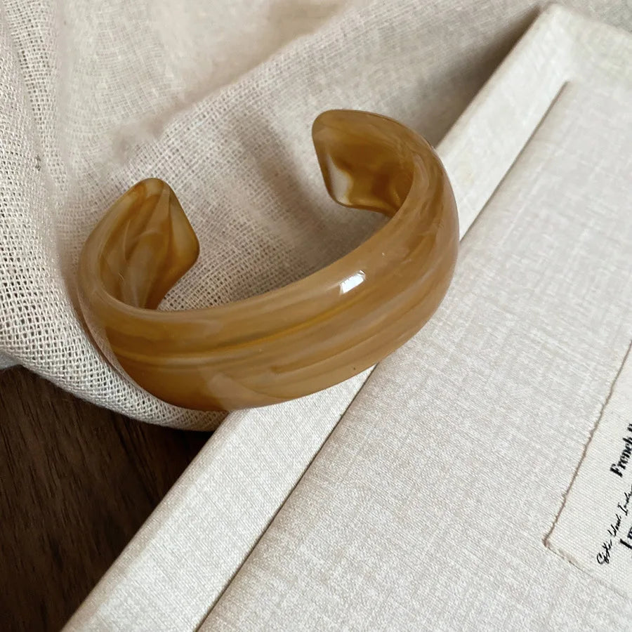 Shiny acrylic open cuff bangle in amber-brown with smooth curved face