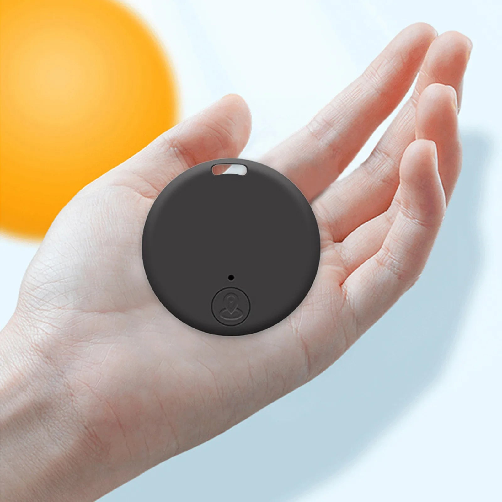 Dark gray round Bluetooth tracker tag held in a hand