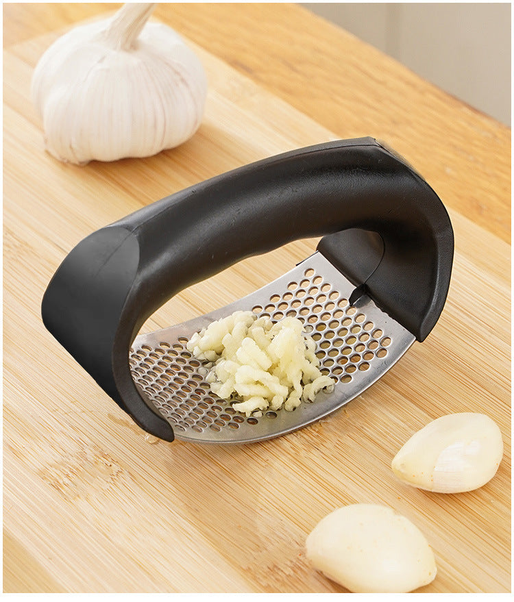 Manual garlic press angled on board, chopped garlic on perforated plate