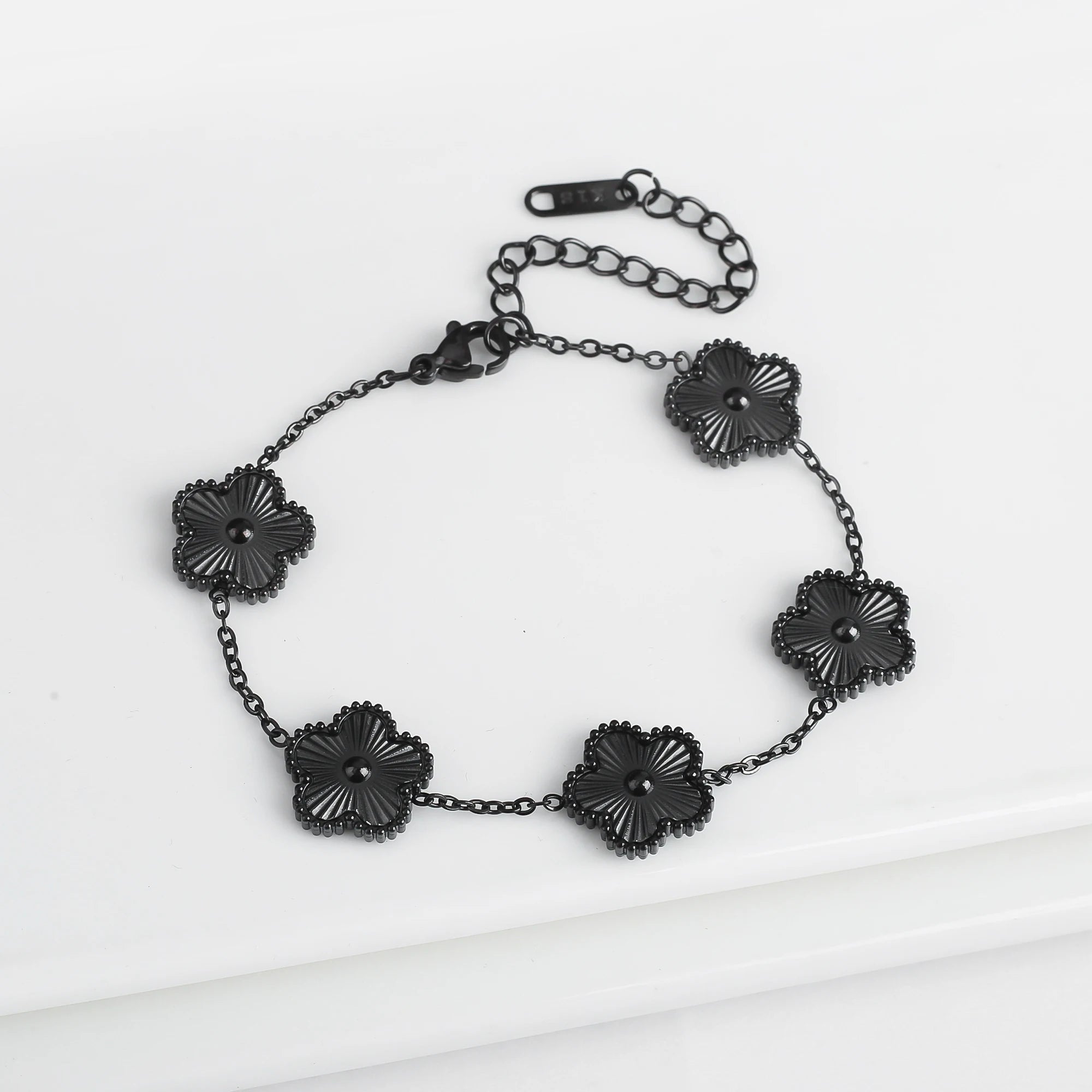 Adjustable black flower charm bracelet with five dark clover-like pendant beads