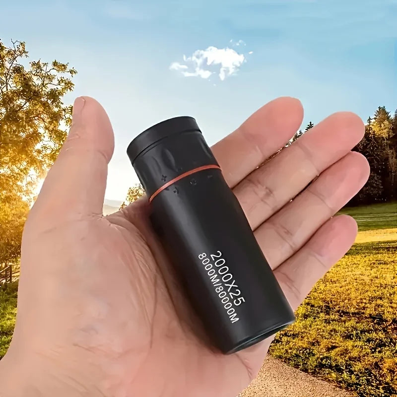 Compact black monocular telescope with red ring, resting in open palm