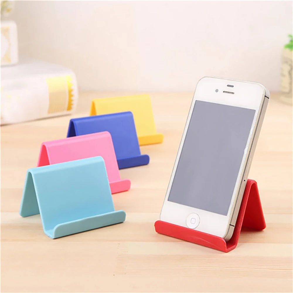 White smartphone propped on red plastic phone holder stand, foldable support