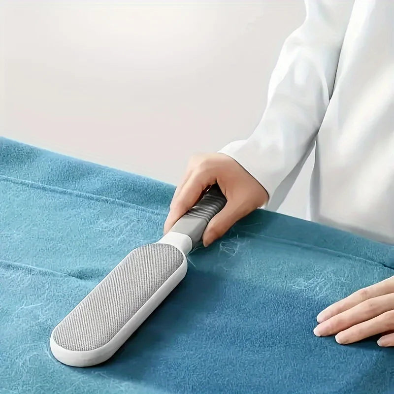 Gray lint brush removing pet hair from a blue fabric sofa cushion