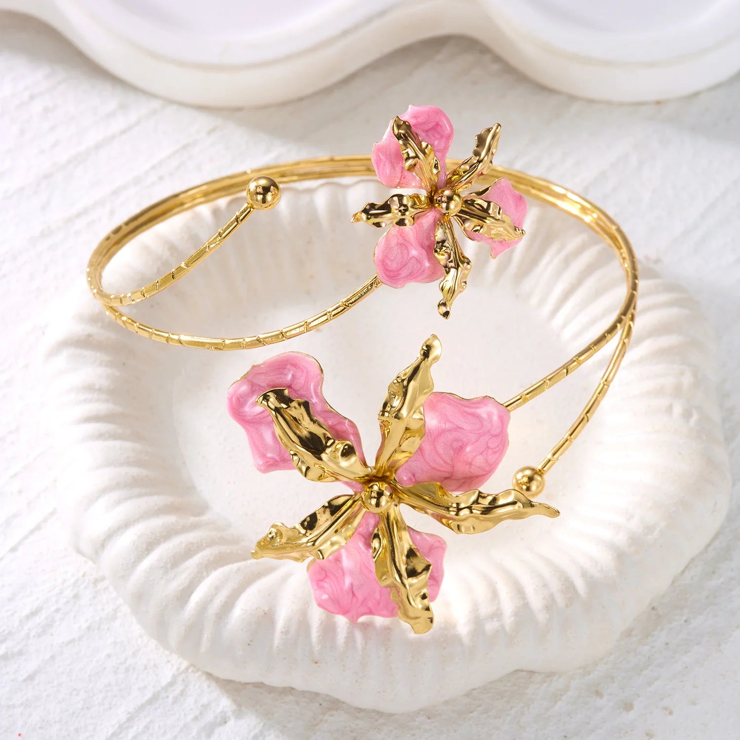 Gold open cuff arm bracelet with two pink enamel flowers and thin chain loop design