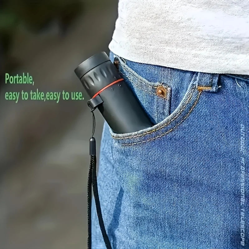 Black monocular telescope clipped to belt loop with strap, shown on blue jeans