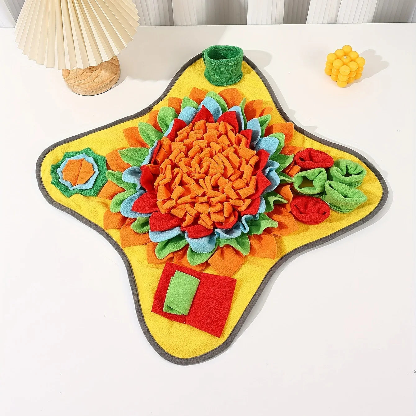 Yellow star-shaped fleece snuffle mat with orange flower center and green pocket pieces