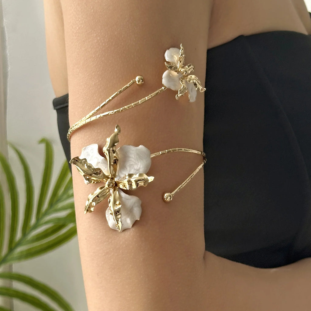 Gold-tone open cuff arm bracelet with white and gold floral enamel charms and beads.